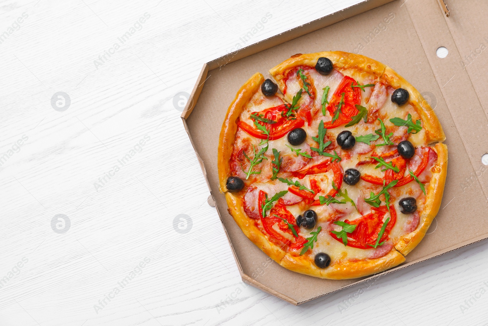 Photo of Cardboard box with tasty pizza on wooden background, top view with space for text