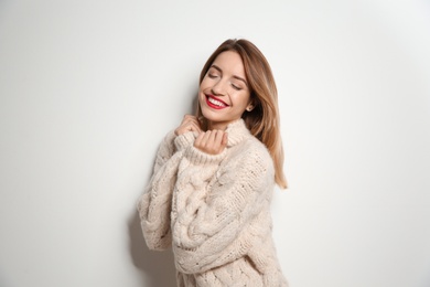 Beautiful young woman in warm sweater on white background