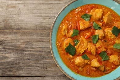 Photo of Delicious chicken curry on wooden table, top view. Space for text