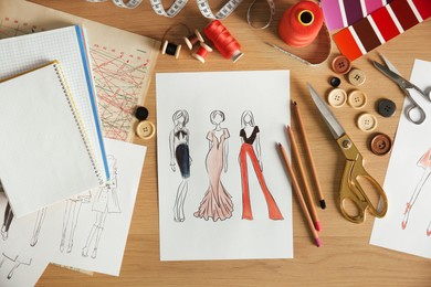 Photo of Sketches of fashion clothes and thread supplies at designer's workplace, flat lay