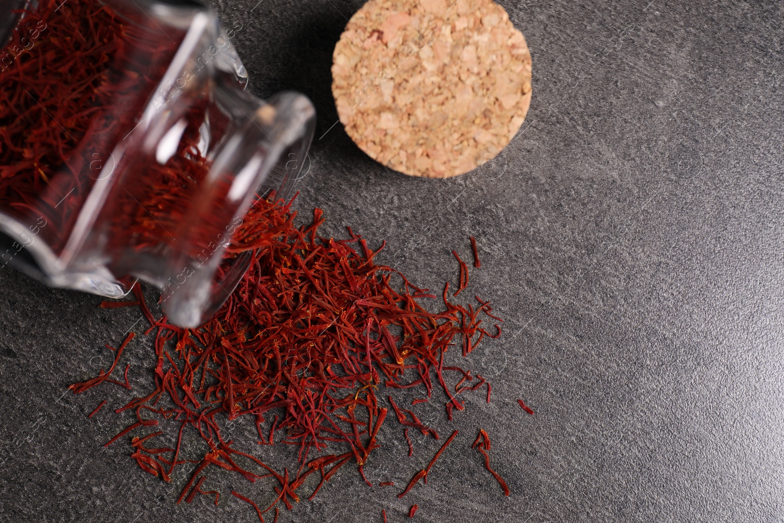 Photo of Aromatic saffron and glass jar on gray table, flat lay. Space for text