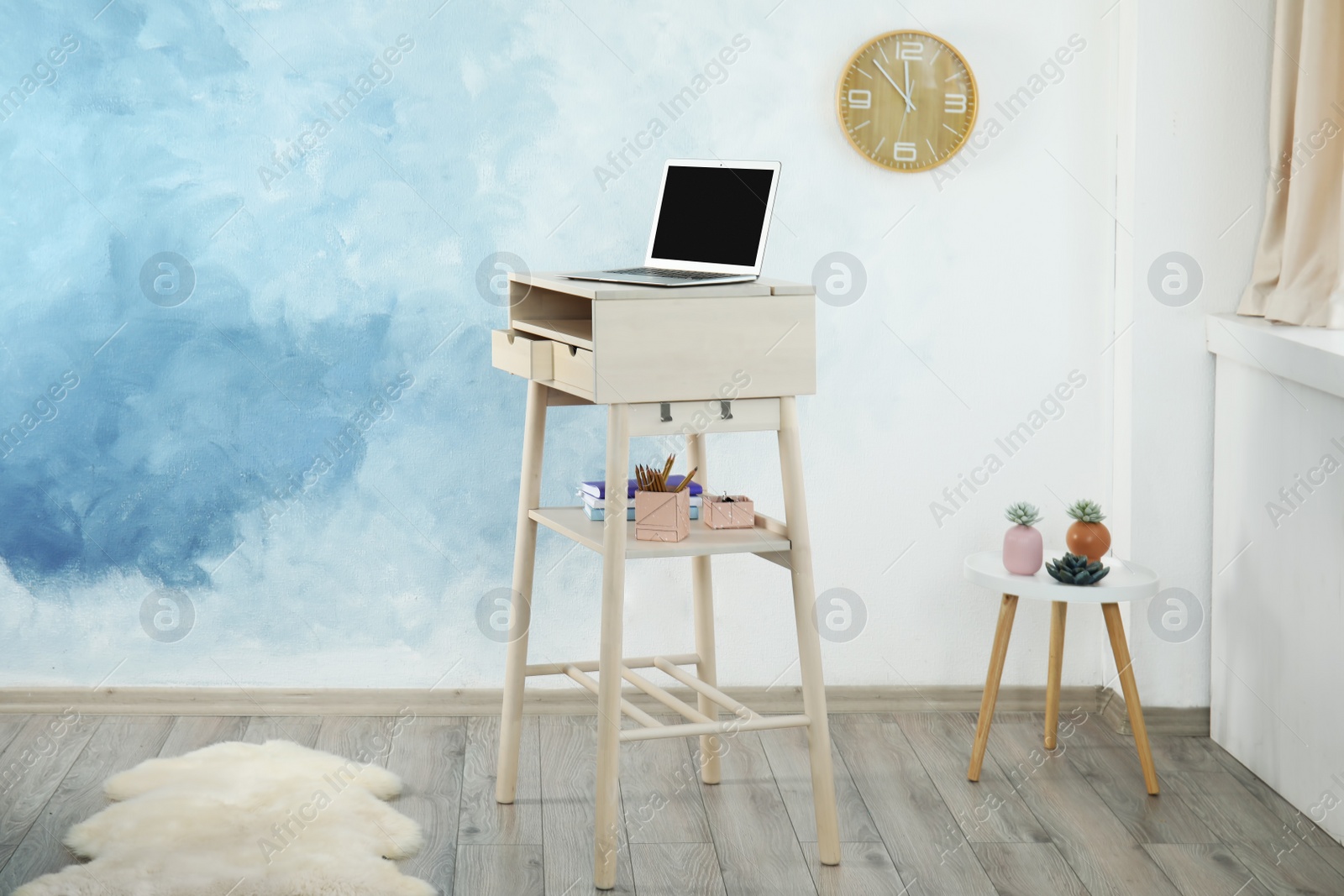 Photo of High wooden table with laptop as stand up workplace in modern interior