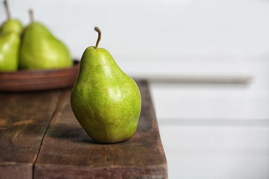 Ripe pear on wooden table against blurred background. Space for text