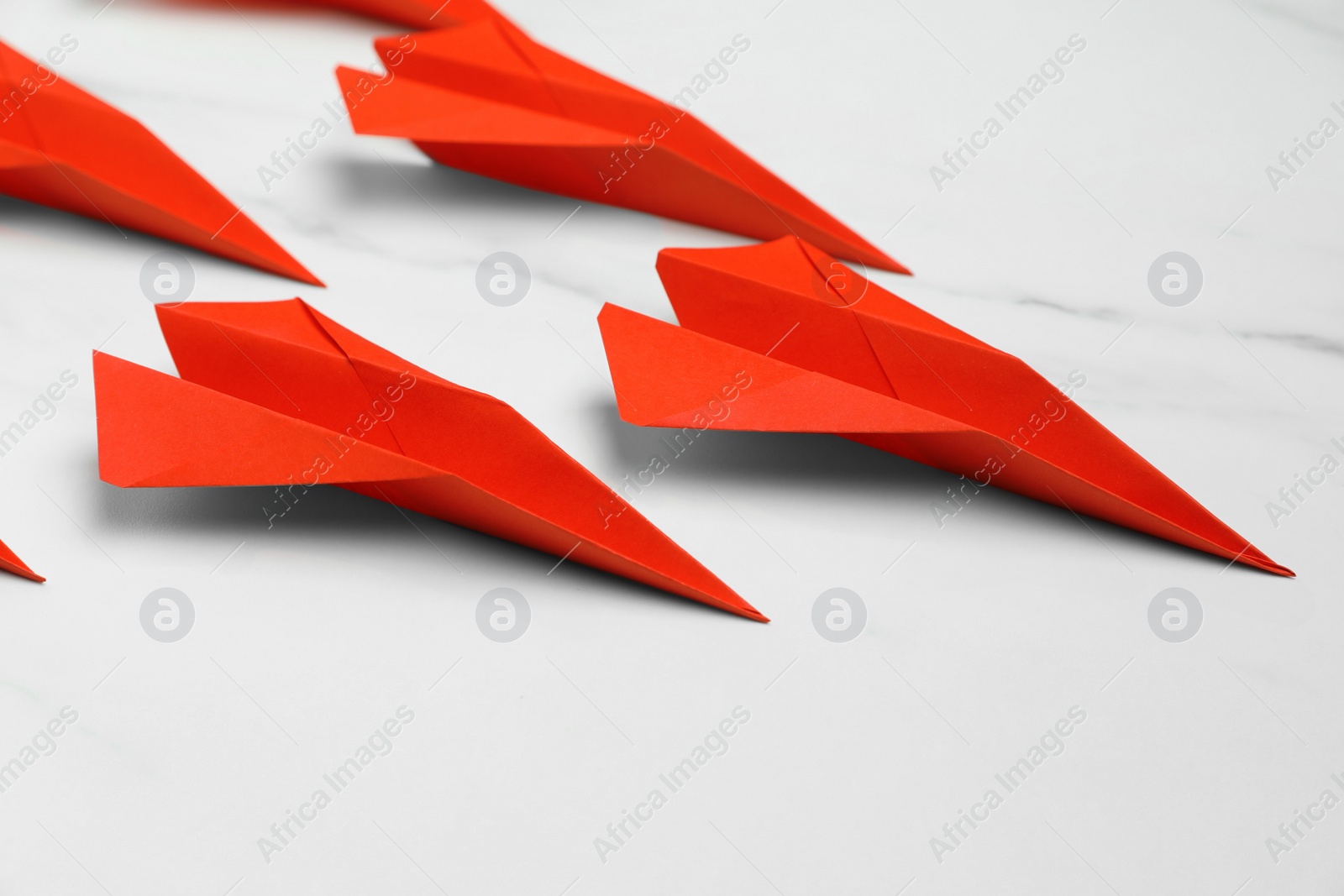 Photo of Many handmade paper planes on white marble table, closeup