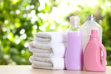 Photo of Soft bath towels and laundry detergents on table against blurred background