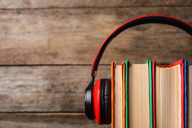 Books and modern headphones on wooden background, closeup. Space for text