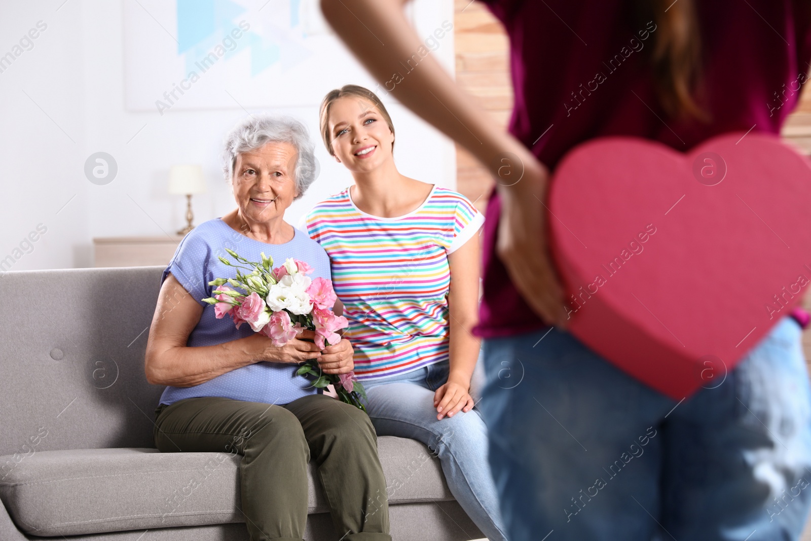 Photo of Preteen girl congratulating her mom and granny at home. Happy Mother's Day