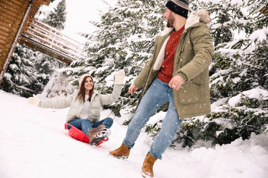 Happy young couple having fun together outdoors on snowy day. Winter vacation