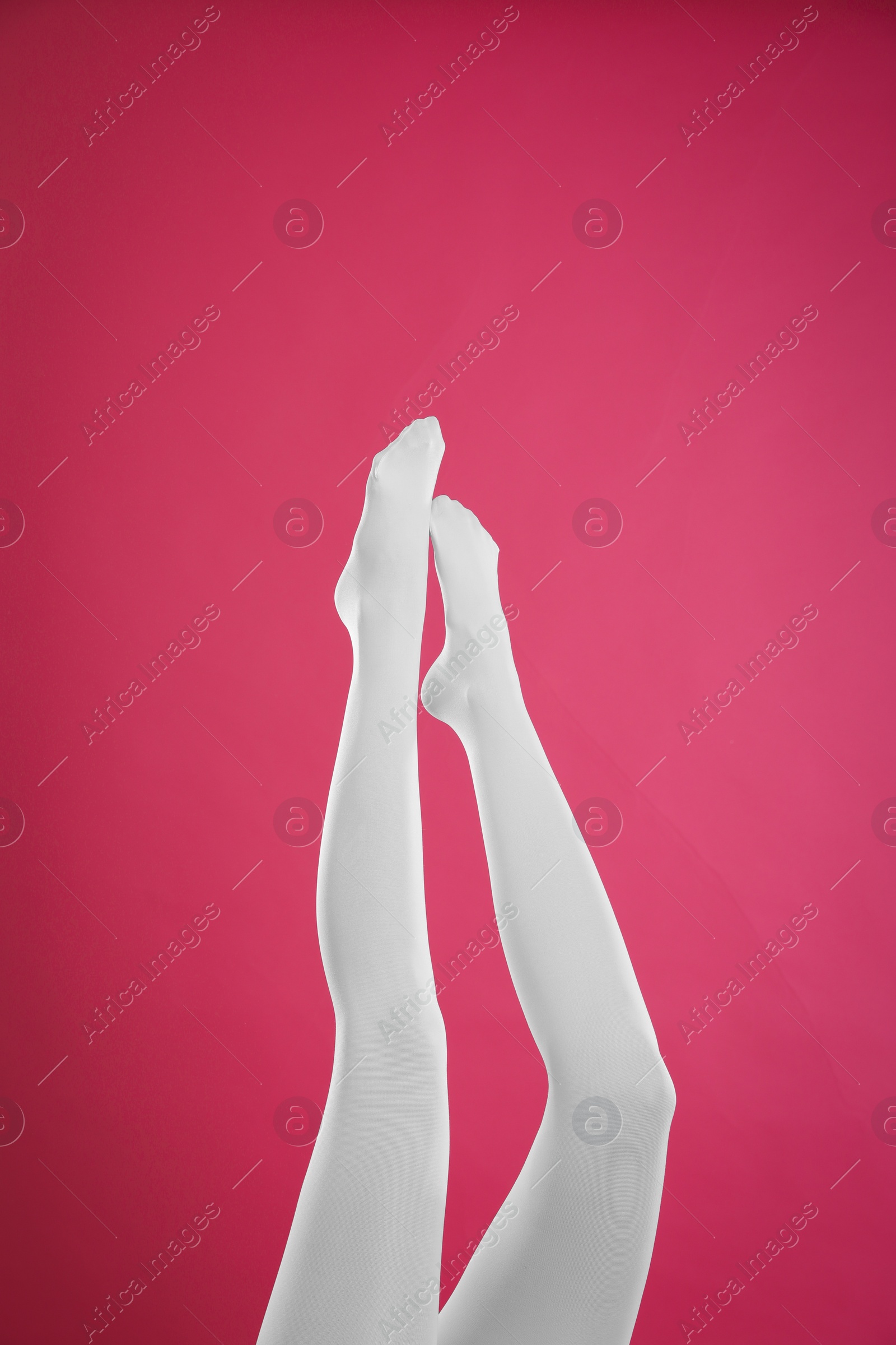 Photo of Woman wearing white tights on crimson background, closeup of legs