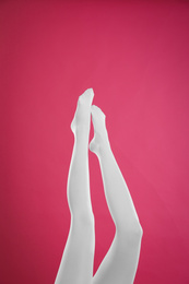 Photo of Woman wearing white tights on crimson background, closeup of legs