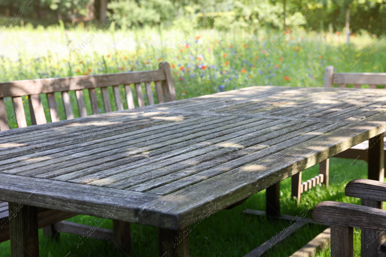 Photo of Empty wooden table with bench on sunny day in garden