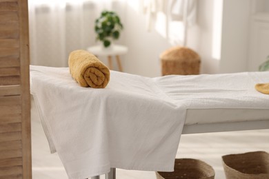 Photo of Comfortable massage table with clean towels in spa center