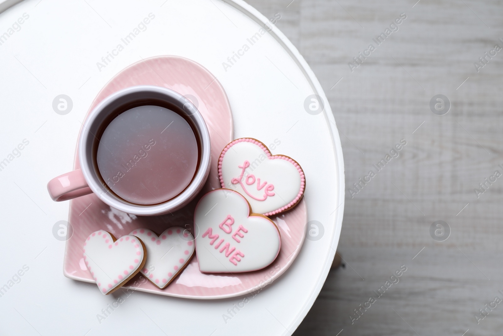 Photo of Delicious heart shaped cookies and cup of tea on white table, top view. Space for text