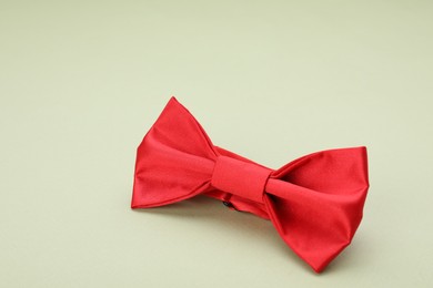 Photo of Stylish red bow tie on pale green background. space for text