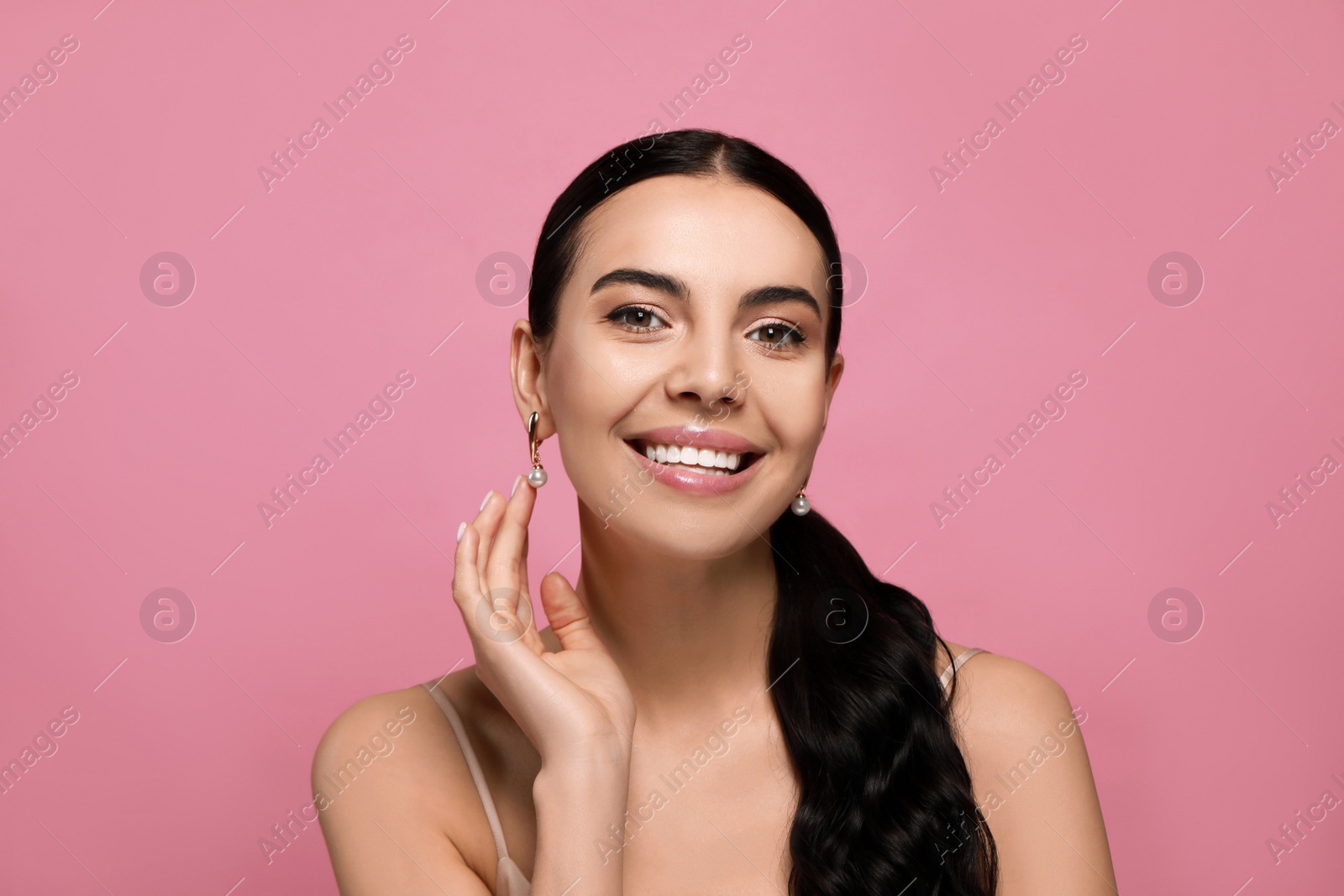 Photo of Young woman wearing elegant pearl earrings on pink background