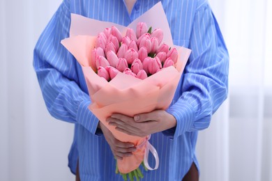 Woman holding bouquet of pink tulips indoors, closeup