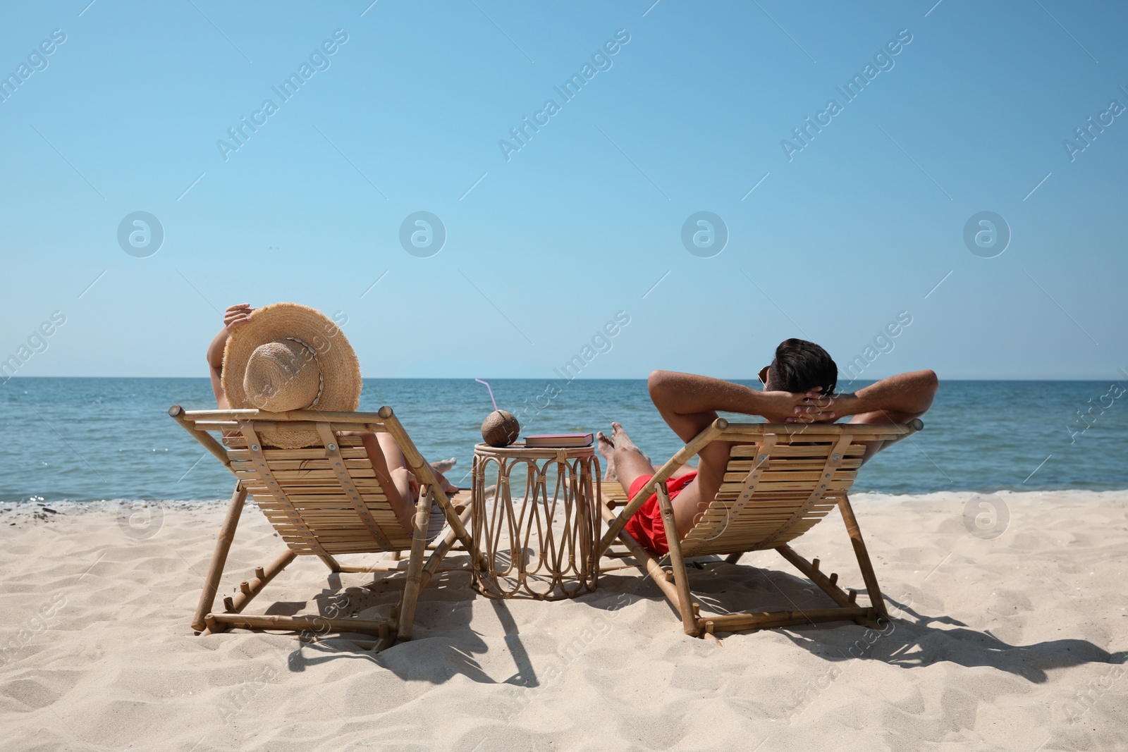 Photo of Couple resting in wooden sunbeds on tropical beach