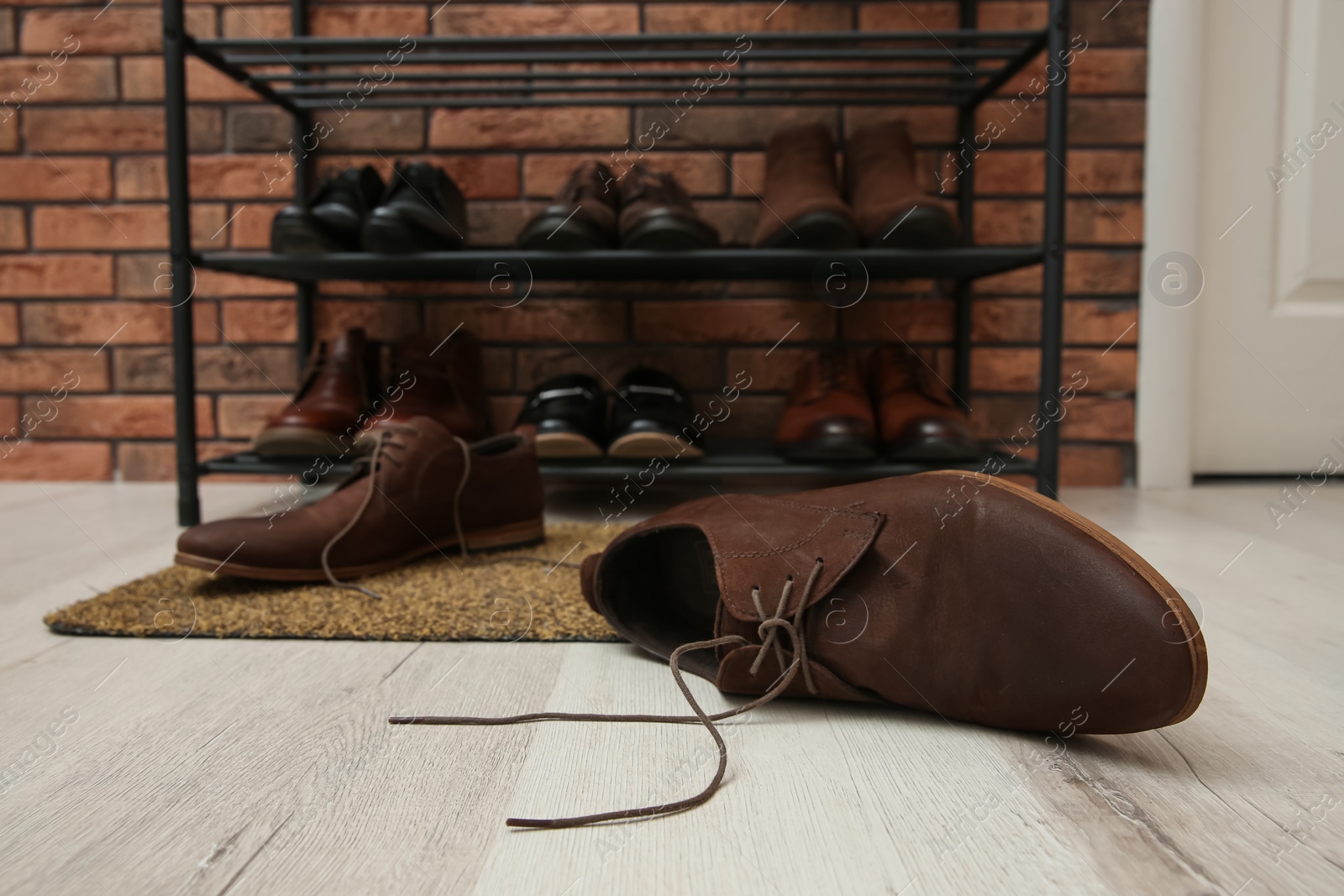 Photo of Shelving unit and stylish shoes on floor in hall