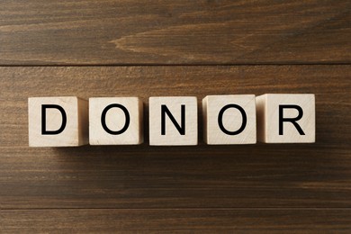 Photo of Word Donor made of cubes on wooden table, top view