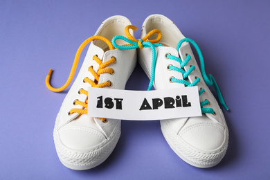 Photo of Shoes tied together and note with phrase 1st APRIL on lilac background. Fool's Day