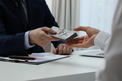 Cashier giving money to businesswoman at desk in bank, closeup