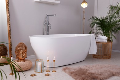Bathroom interior with golden Buddha sculpture and modern white tub