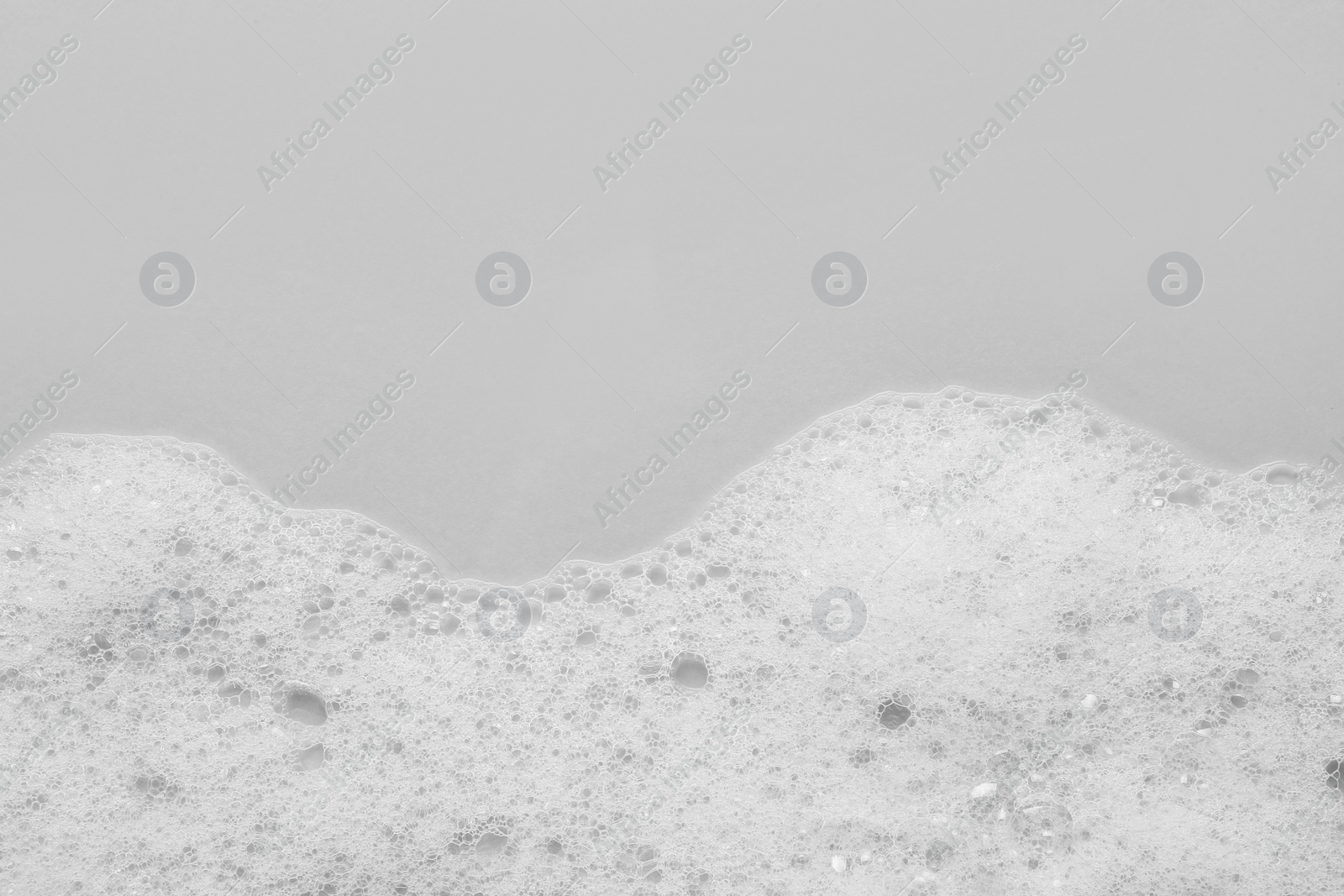 Photo of Fluffy bath foam on light background, top view. Space for text