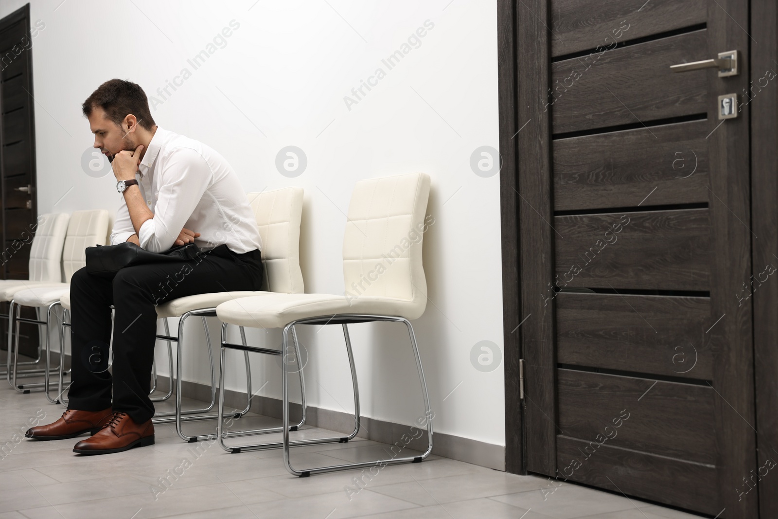 Photo of Man with briefcase waiting for job interview indoors