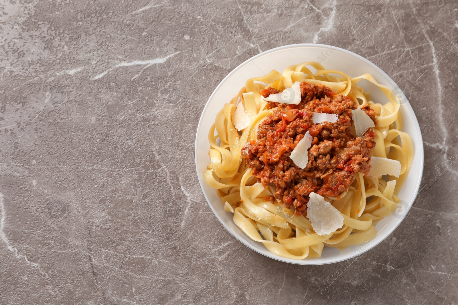 Photo of Plate with delicious pasta bolognese on grey background, top view