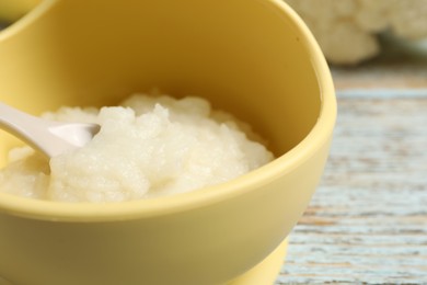 Baby food. Bowl with cauliflower puree on rustic wooden table, closeup