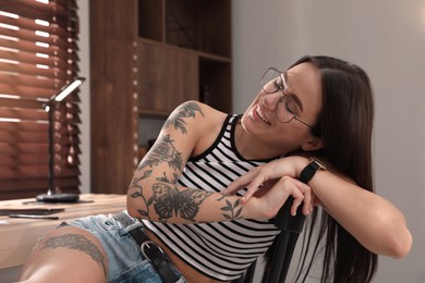 Photo of Beautiful young woman with tattoos on body indoors