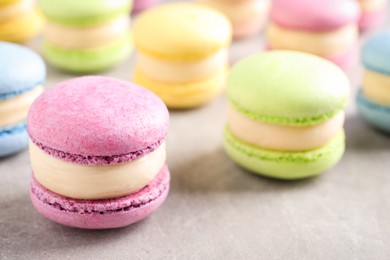 Photo of Many delicious colorful macarons on grey table, closeup