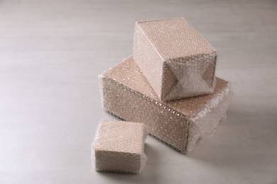 Photo of Cardboard boxes covered with bubble wrap on light grey table