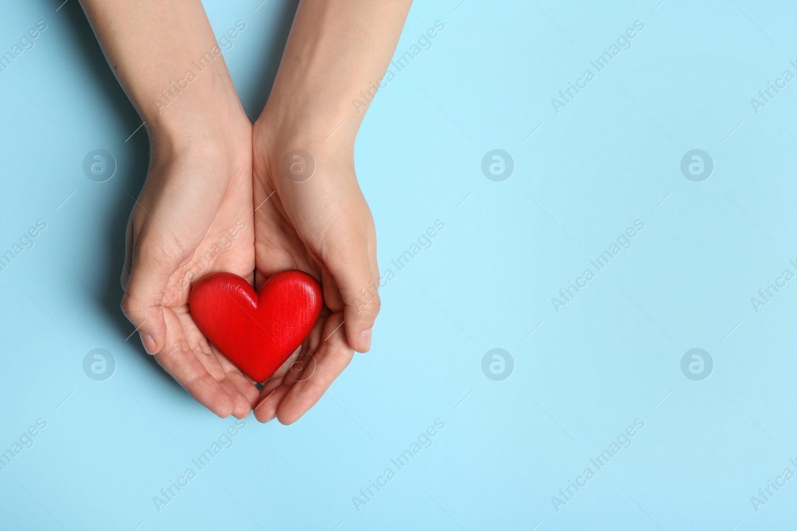 Photo of Woman holding heart on blue background, top view with space for text. Donation concept