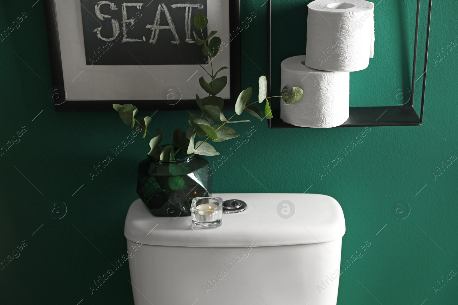 Photo of Decor elements, paper rolls and toilet bowl near green wall. Bathroom interior