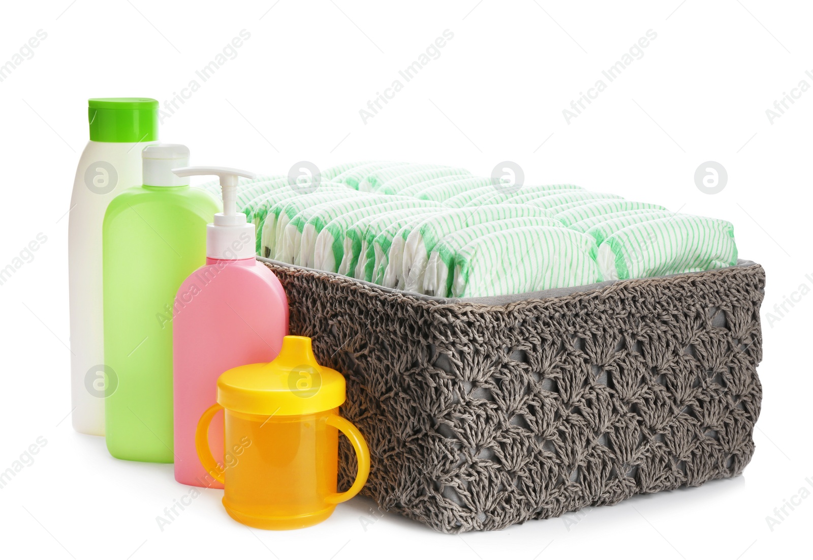 Photo of Basket with diapers and baby accessories on white background