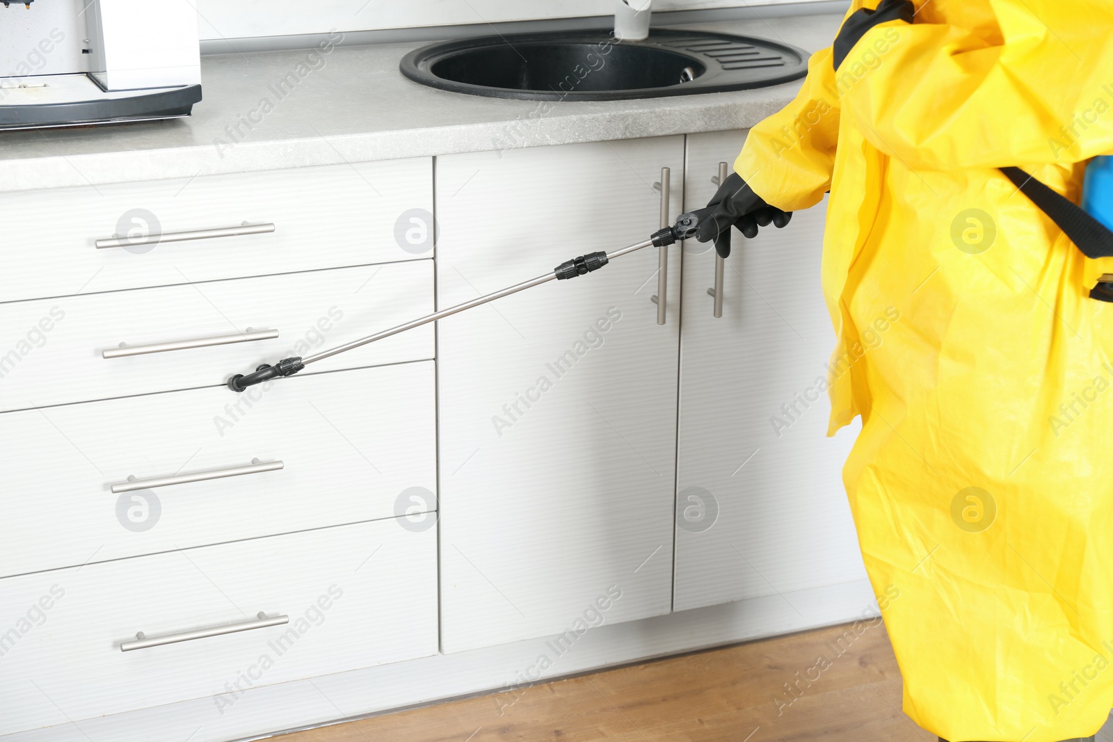 Photo of Pest control worker spraying pesticide in kitchen, closeup