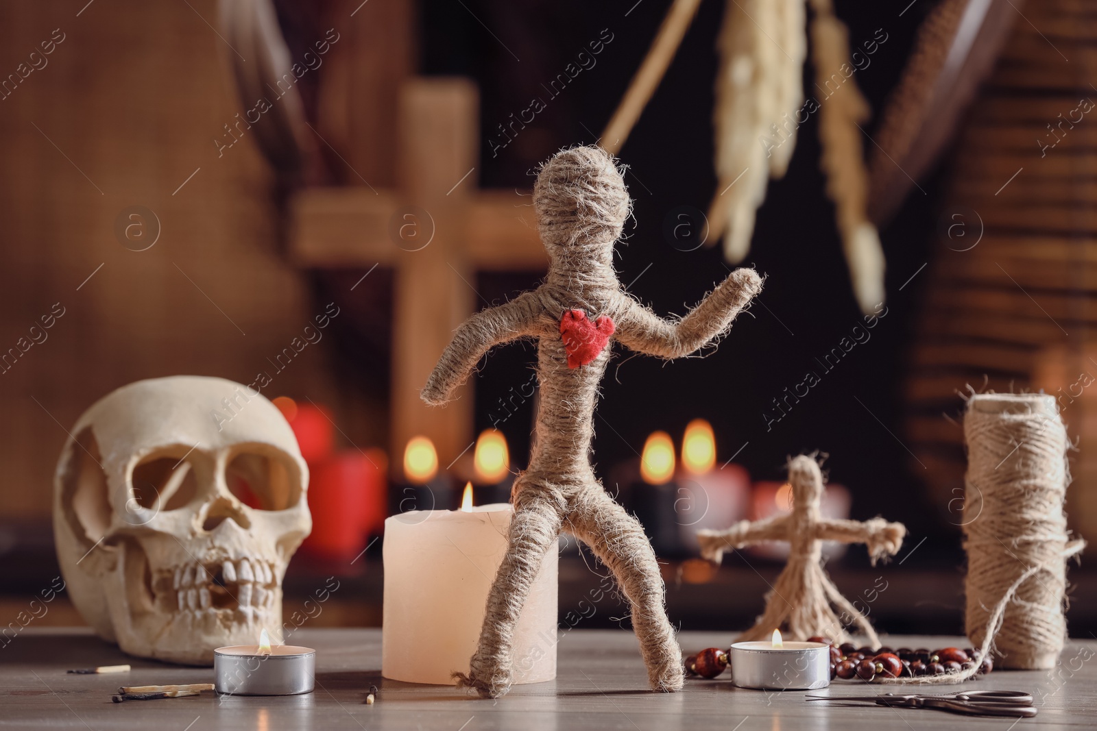 Photo of Voodoo doll with heart and ceremonial items on wooden table