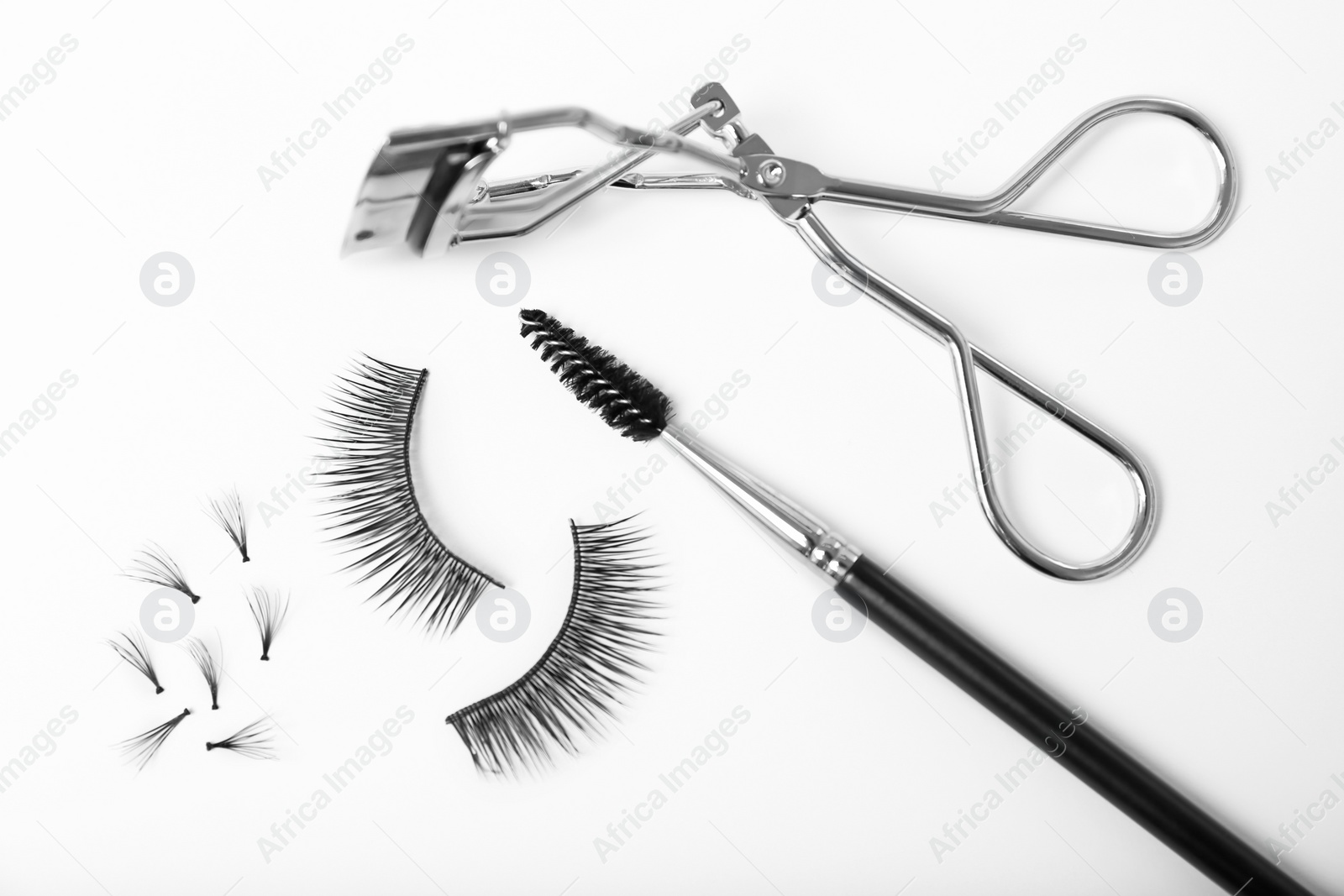 Photo of False eyelashes, brush and curler on white background