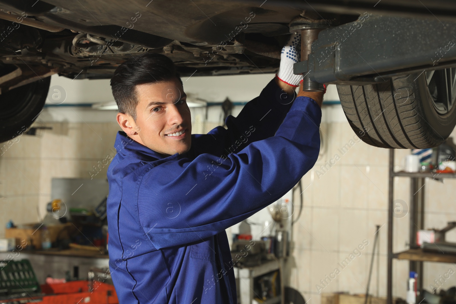 Photo of Professional mechanic fixing lifted car at automobile repair shop