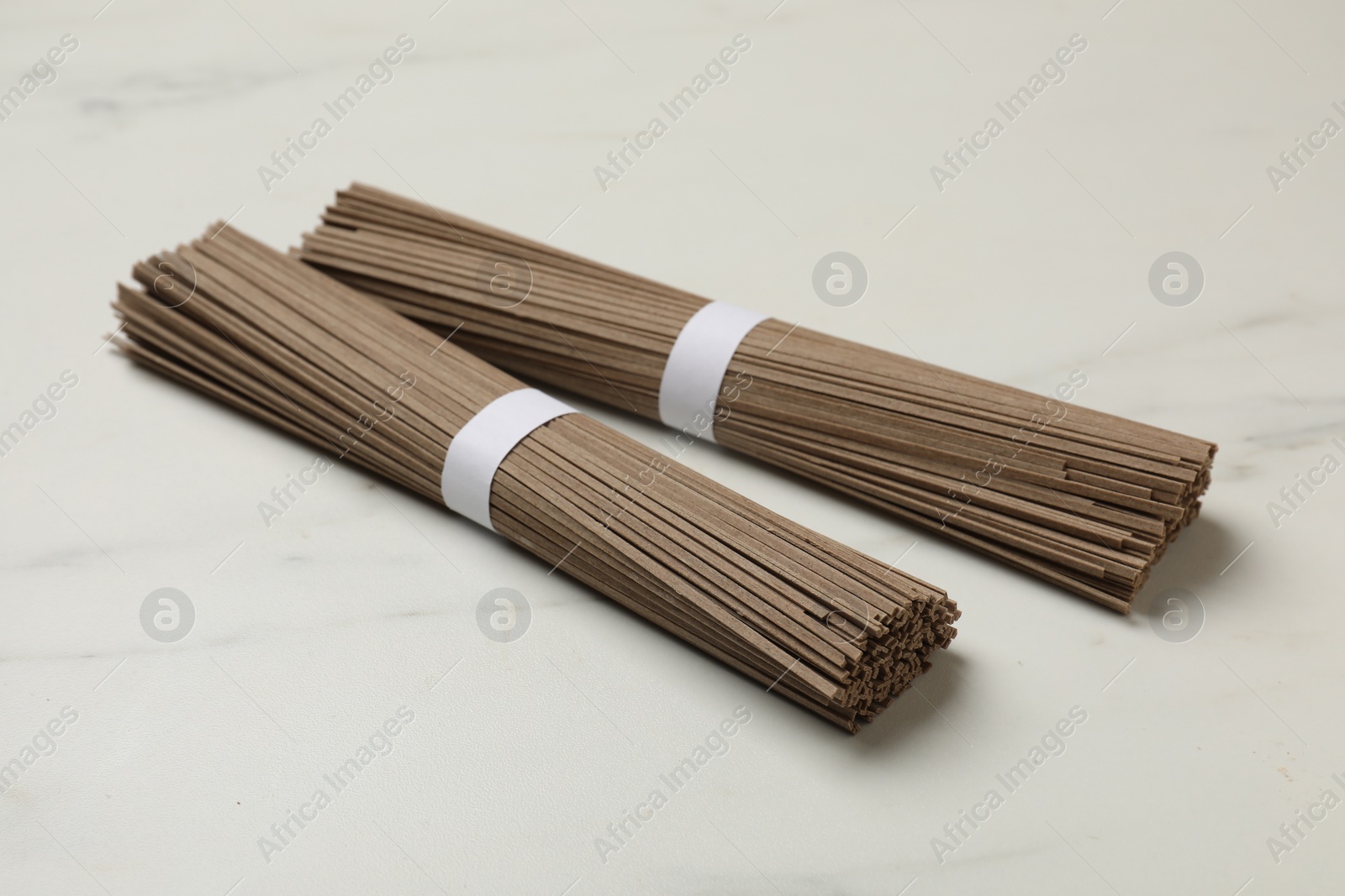 Photo of Uncooked buckwheat noodles (soba) on white marble table