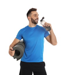 Handsome man with yoga mat drinking water on white background