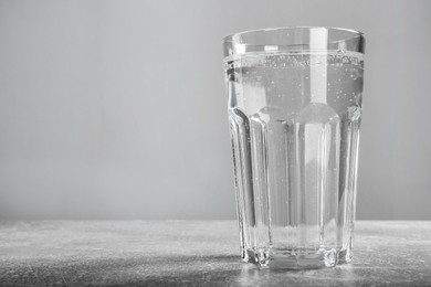 Photo of Glass of soda water on grey background. Space for text