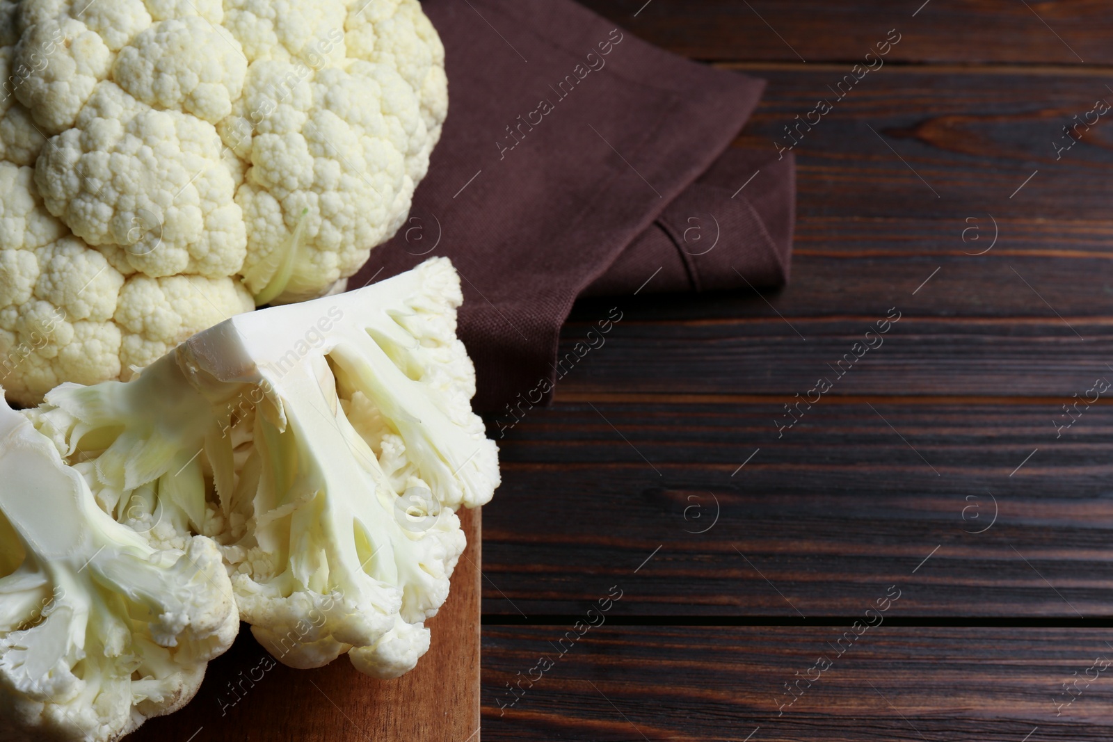 Photo of Fresh raw cauliflower on wooden table. Space for text