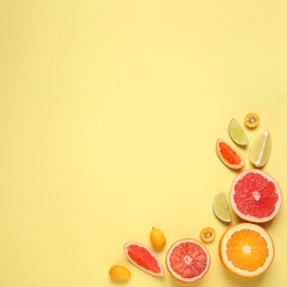 Photo of Fresh juicy citrus fruits on light yellow background, flat lay. Space for text