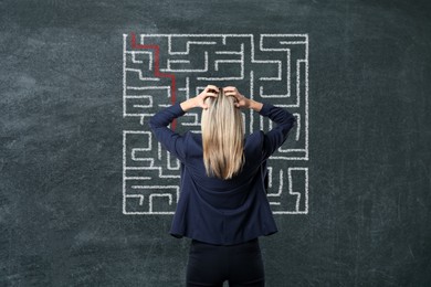 Image of Businesswoman looking at chalkboard with illustration of maze