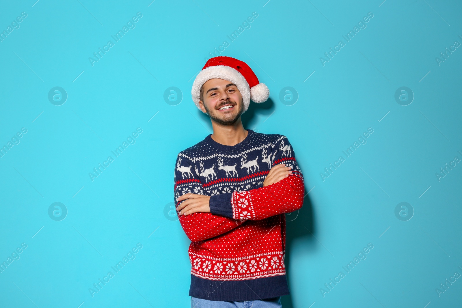 Photo of Young man in Christmas sweater and hat on color background