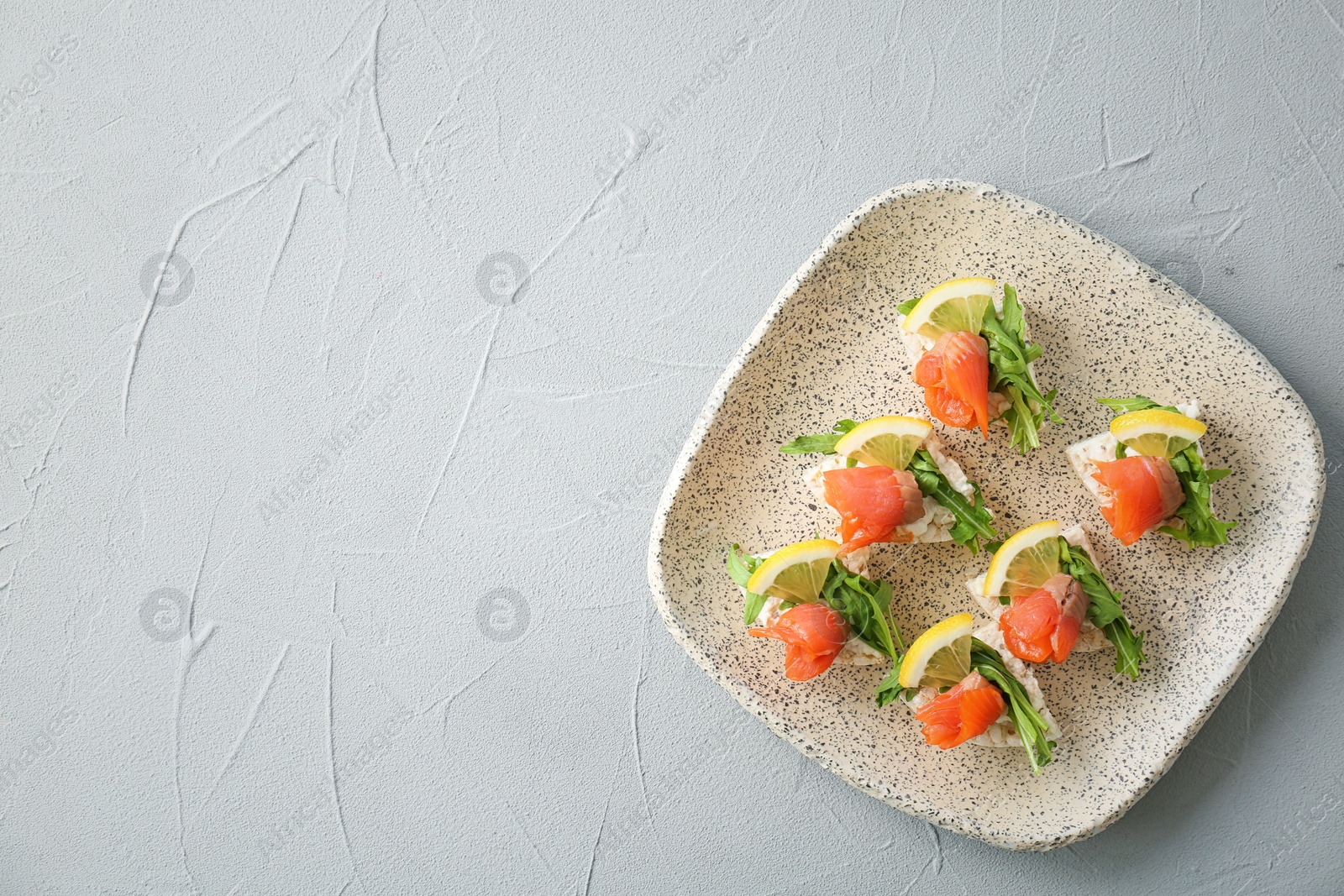 Photo of Plate of crispbreads with fresh sliced salmon fillet on table, top view