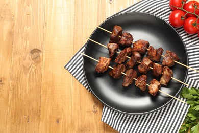 Photo of Delicious shish kebabs with vegetables on wooden table, flat lay. Space for text