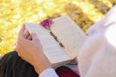Photo of Woman reading book outdoors on sunny autumn day, closeup